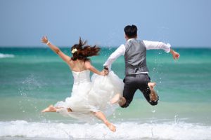 Brautpaar macht Luftsprung am Meer